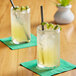Two glasses of Tractor Beverage Co. Organic Limeade with yellow liquid and straws on a table.