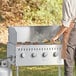 A man using a Backyard Pro wind guard to cook food on a grill with a gas burner.
