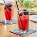 Two glasses of Tractor Beverage Co. blackberry juice on a table with black straws and berries.