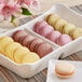 A tray of White Toque French Exotic assorted macarons on a table in a bakery display.