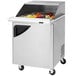 A Turbo Air stainless steel refrigerated sandwich prep table with food on the counter.