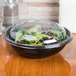 A Sabert FreshPack clear dome lid on a salad bowl filled with salad.