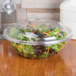 A salad in a Sabert clear plastic bowl with a clear plastic lid.