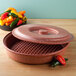 A red Polyethylene HS Inc. "Tortilla Pleezer" with a lid on a counter with colorful peppers.