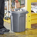 A man putting a plastic bag into a Toter dark gray granite round trash can.