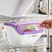 A white and purple plastic ingredient bin with a flip lid, label sheet, and scoop, used for storing rolled oats.