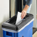 A hand putting a piece of paper into a blue Toter recycle lid.