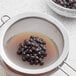A sieve with Fanale black tapioca pearls in it.