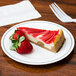 A slice of cheesecake with a strawberry on a WNA Comet white plastic plate with silver accent bands.