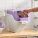 A large white and purple ingredient bin with a flip lid, labeled for brown sugar, being used to scoop contents.