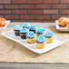 A wavy stoneware platter with cupcakes frosted blue and sprinkled on top.