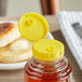 A plastic container of honey with a yellow flip top lid.