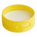 A yellow plastic lid with a white pressure sensitive liner.