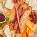 A cutting board with Shaffer Venison Farms venison snack sticks, cheese, grapes, and crackers.