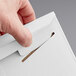 A hand opening a white Lavex Stayflats rigid mailer box.