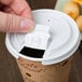 A hand using a Solo White Tear Tab Lid to open a coffee cup.