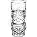 A close-up of a clear Acopa tiki glass with a face design.