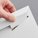 A hand using a paper clip to open a Lavex Stayflats white envelope.