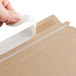 A hand seals a brown Lavex Stayflats mailer with white tape.