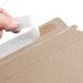 A person using Lavex Stayflats Kraft mailer tape to seal a piece of paper.