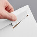 A hand using a paper clip to open a white Lavex Stayflats rigid mailer.