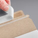 A person using a white Lavex Stayflats self-sealing mailer to hold a piece of paper.