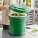 A person using a Garde salad spinner to dry greens in a green container.