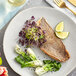 A plate with a wild caught black sea bass fillet and vegetables with a lime wedge.