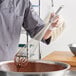 A person using a Choice stainless steel French whisk to mix chocolate batter in a bowl.