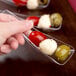 A hand holding a Fineline clear plastic spoon filled with food.