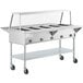 A ServIt open well electric steam table on wheels with an angled sneeze guard and tray slide.