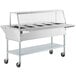 A ServIt stainless steel electric steam table on wheels with an angled glass sneeze guard.
