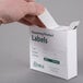 A hand holding a white Noble Products box of dissolvable product labels with green text on the label.
