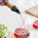 A Franmara Black Dripless Wine Pourer pouring red wine from a bottle into a glass.