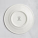 A white RAK Porcelain flat plate with an embossed crown logo on the rim.