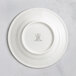 A white RAK Porcelain flat plate with an embossed crown logo on the rim.