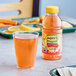 A bottle of Mott's Fruit Punch next to a glass of orange juice on a table.