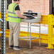 A man in a safety vest standing next to a Lavex Stainless Steel Locking Receiving Desk.