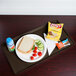 A Brazil brown Cambro dietary tray with food including a sandwich, chips, and a drink on it.