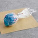 A blue ball of cake with pink sprinkles in plastic wrap.