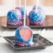 A black plate with Chalet Desserts blue and pink frosted cake pops.