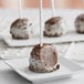 A chocolate covered cake pop on a white plate.