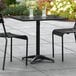 A Lancaster Table & Seating black outdoor table with two chairs on a patio.
