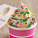 A cup of ice cream with Nerds candy topping and sprinkles.