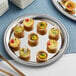 An American Metalcraft stainless steel serving tray with mini quiches on it on a table.