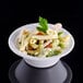 A white Dart foam bowl filled with pasta salad with a leafy green garnish.