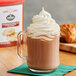 A glass mug of Land O Lakes Cocoa Classics Chocolate Snickerdoodle cocoa with a croissant on the side.