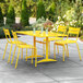 A yellow Lancaster Table & Seating dining table and chairs on a patio.