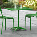 A green Lancaster Table & Seating outdoor table with two chairs on a stone patio.