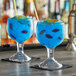 Two customizable GET SAN plastic schooners filled with blue liquid and straws on a table.
